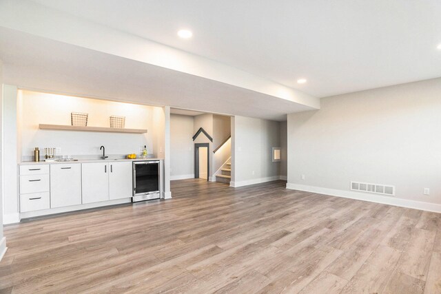 bar with sink, white cabinetry, beverage cooler, and light hardwood / wood-style flooring