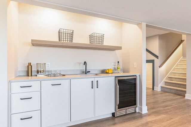 bar featuring white cabinetry, wine cooler, light hardwood / wood-style flooring, and sink