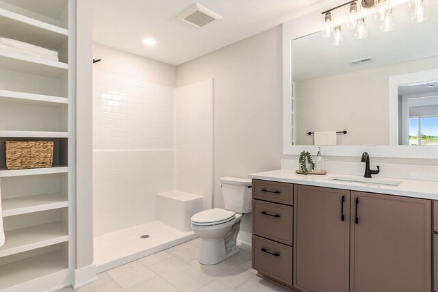 bathroom featuring toilet, vanity, tile patterned floors, and tiled shower