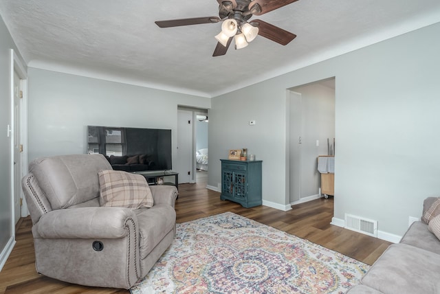 living room featuring ceiling fan, a textured ceiling, and dark hardwood / wood-style flooring