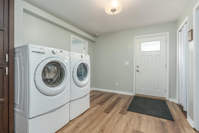 laundry room with washing machine and clothes dryer and light hardwood / wood-style floors