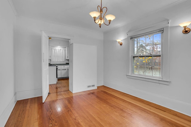 spare room with hardwood / wood-style flooring, a notable chandelier, and ornamental molding