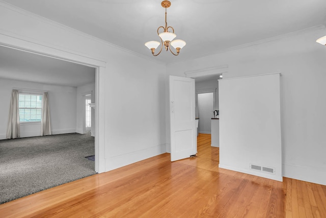 empty room with ornamental molding, hardwood / wood-style floors, and a chandelier