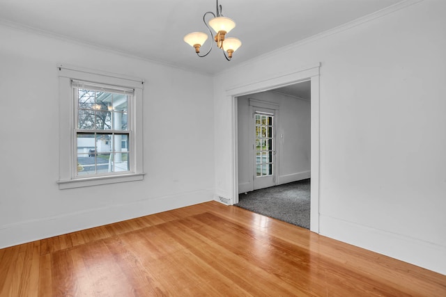 empty room with hardwood / wood-style floors, crown molding, and an inviting chandelier