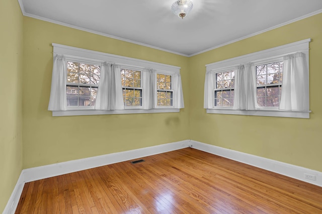 spare room with hardwood / wood-style flooring, a healthy amount of sunlight, and crown molding