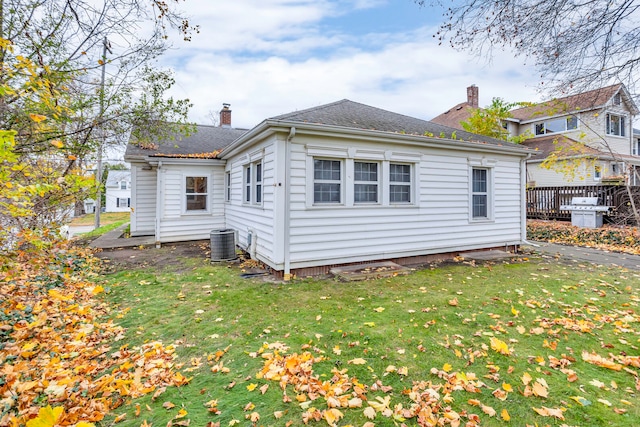 rear view of house with central air condition unit and a yard