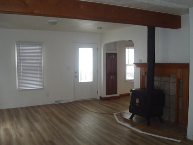 foyer featuring hardwood / wood-style flooring, a wood stove, and beamed ceiling