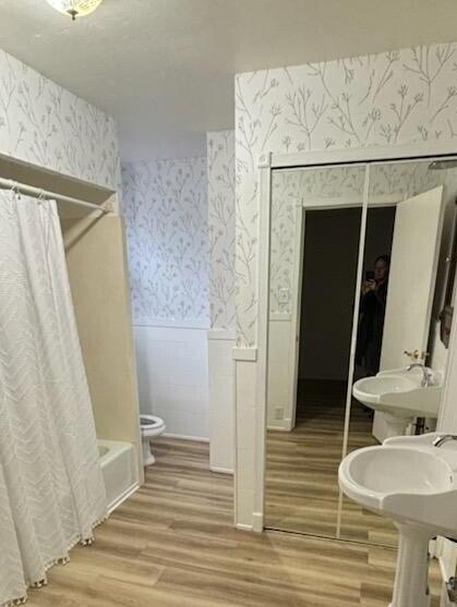 bathroom with shower / bath combination with curtain, hardwood / wood-style flooring, and toilet