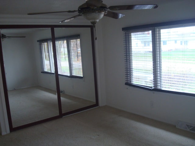 unfurnished bedroom featuring ceiling fan, a closet, carpet floors, and multiple windows