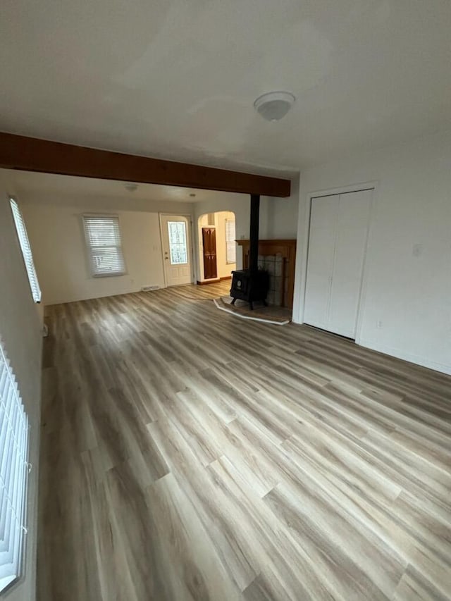 unfurnished living room with light wood-type flooring and a wood stove