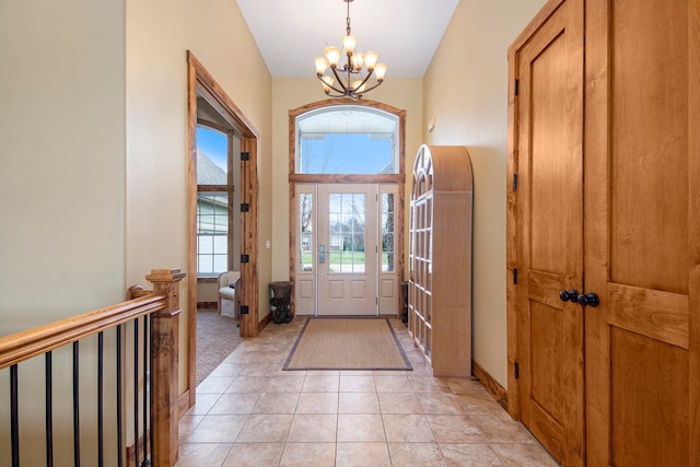 tiled foyer featuring lofted ceiling and an inviting chandelier