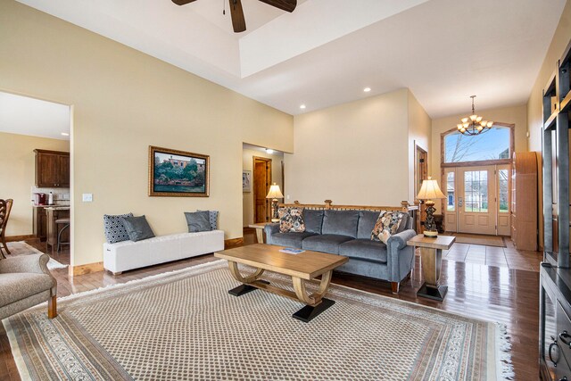 living room featuring a high ceiling, wood-type flooring, and ceiling fan with notable chandelier