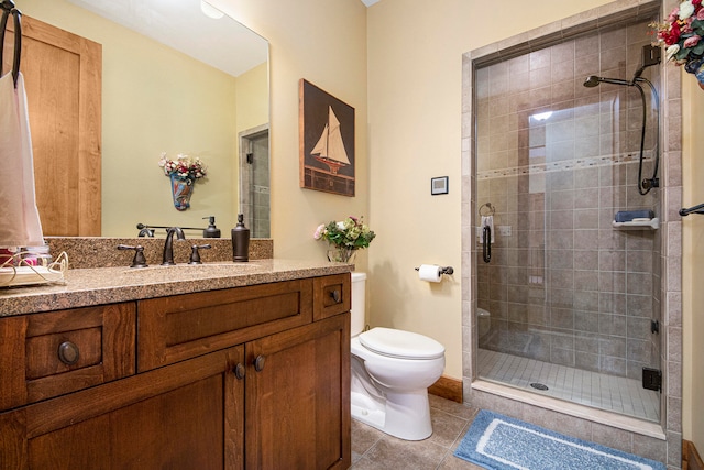 bathroom with tile patterned flooring, vanity, toilet, and a shower with shower door