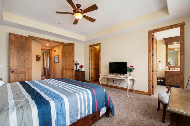 bedroom featuring carpet flooring, a raised ceiling, ceiling fan, and ensuite bathroom