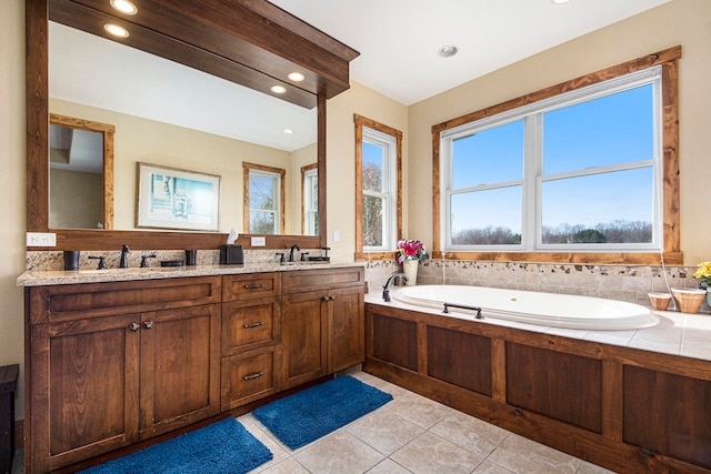 bathroom with tile patterned floors, a tub to relax in, and vanity