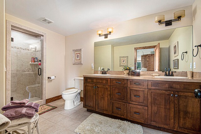 bathroom featuring tile patterned flooring, vanity, a shower with shower door, and toilet