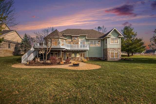 back house at dusk featuring a patio area, a yard, and a wooden deck