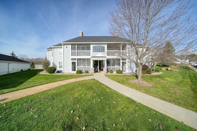 view of front of house with a front yard and a sunroom