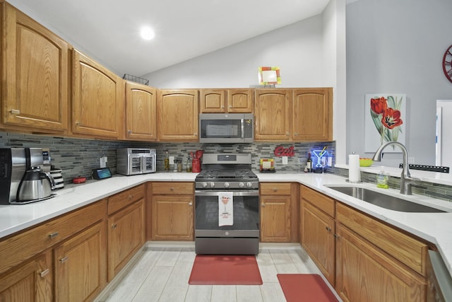 kitchen with decorative backsplash, sink, stainless steel appliances, and vaulted ceiling