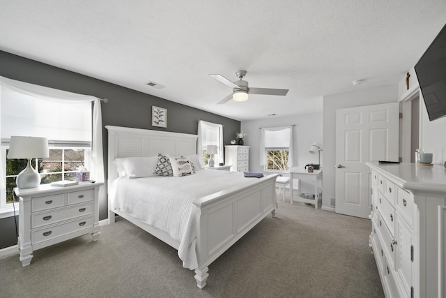 bedroom featuring ceiling fan, dark carpet, and a textured ceiling