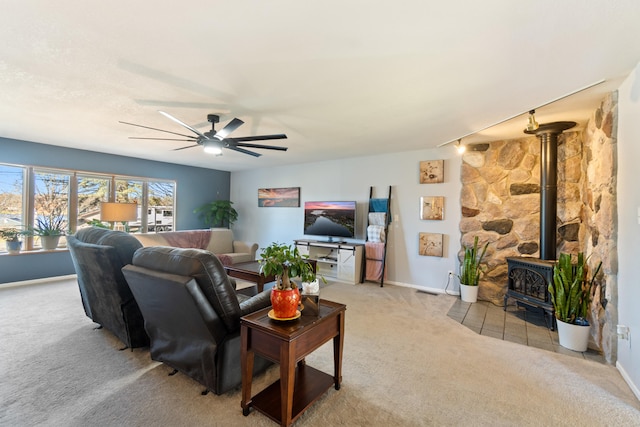 living room featuring ceiling fan, a wood stove, and light carpet