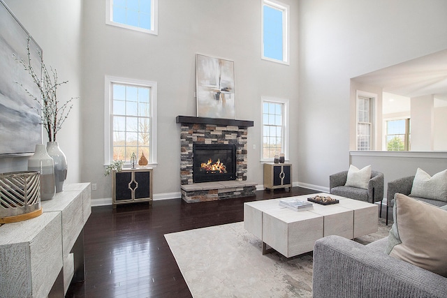 living room featuring a fireplace, dark wood-type flooring, and a high ceiling