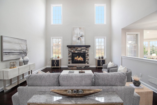 living room featuring a fireplace, a high ceiling, hardwood / wood-style flooring, and a healthy amount of sunlight