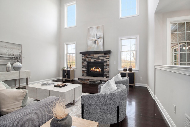 living room with dark hardwood / wood-style flooring, a fireplace, and a high ceiling