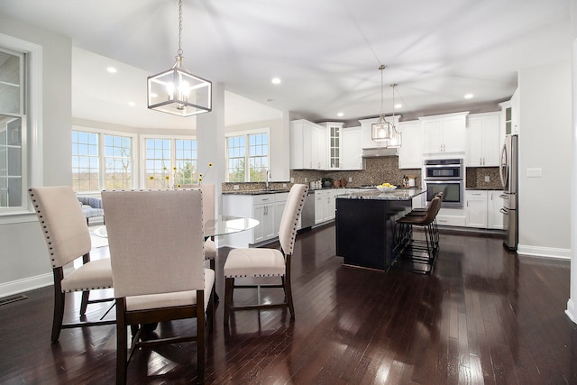 dining space featuring a notable chandelier, dark wood-type flooring, and sink