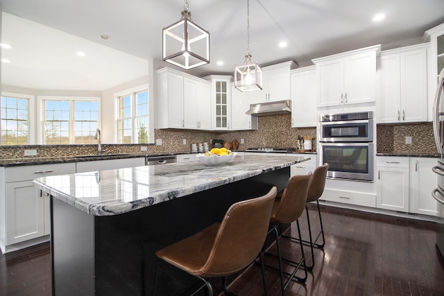 kitchen featuring dark hardwood / wood-style flooring, backsplash, a kitchen island, and sink