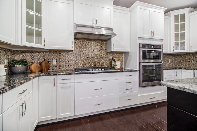 kitchen with double oven, backsplash, white cabinets, and dark hardwood / wood-style floors