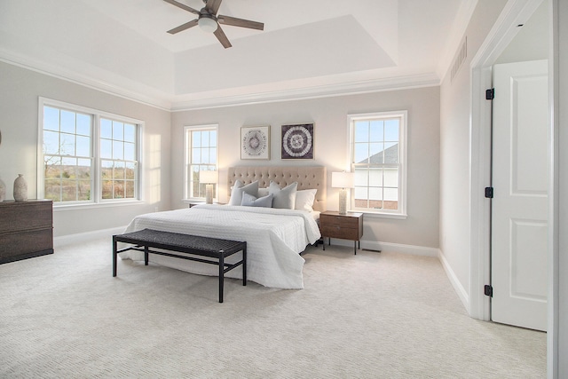 carpeted bedroom with a tray ceiling and ceiling fan