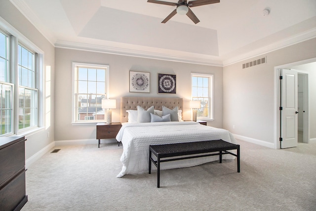 bedroom with ceiling fan, ornamental molding, light carpet, and a tray ceiling