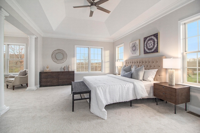 carpeted bedroom featuring decorative columns, a tray ceiling, multiple windows, and ceiling fan