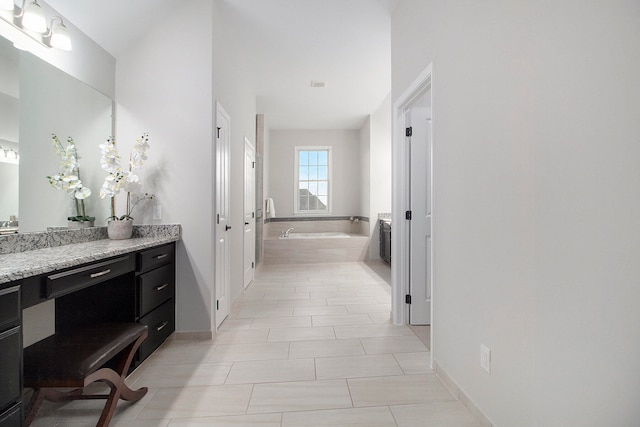 bathroom featuring tile patterned floors, tiled tub, and vanity