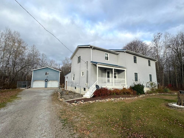 view of front of house featuring covered porch, a garage, a front yard, and an outbuilding