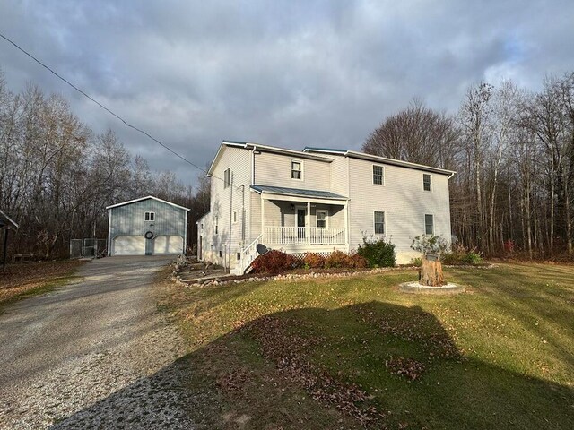 exterior space featuring a front lawn, a garage, a porch, and an outbuilding