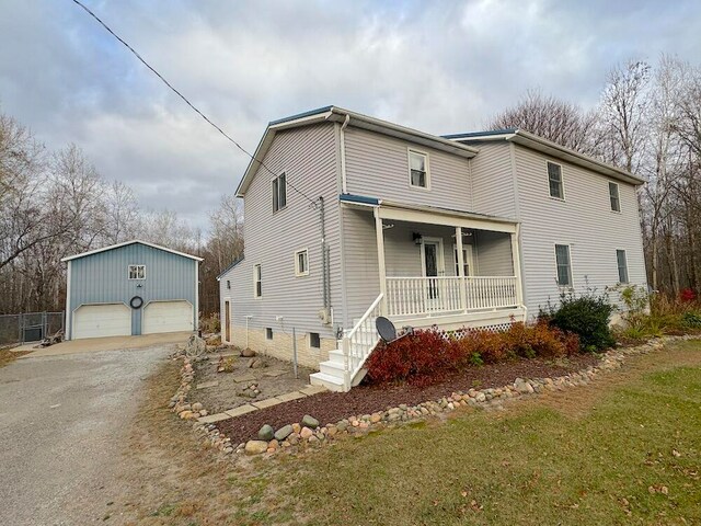 view of front of home featuring a garage, an outdoor structure, and covered porch