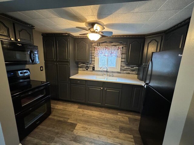 kitchen with dark wood-type flooring, decorative backsplash, black appliances, sink, and ceiling fan