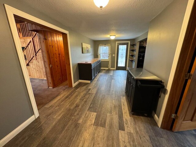 hall featuring dark wood-type flooring and a textured ceiling