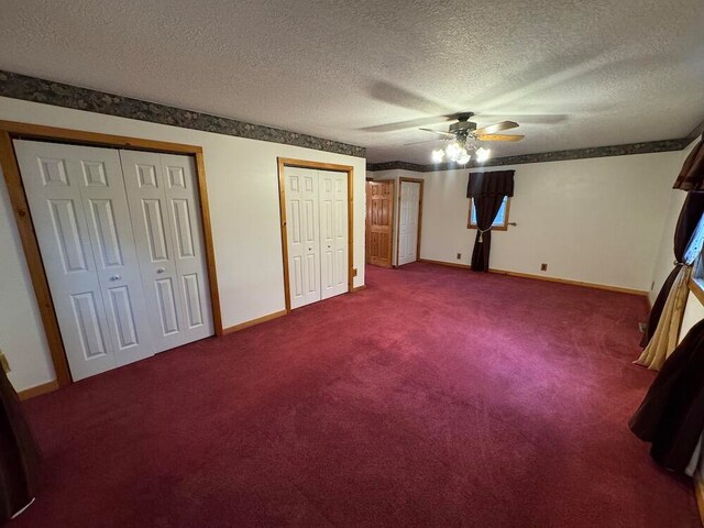 unfurnished bedroom with a textured ceiling, two closets, ceiling fan, and carpet floors