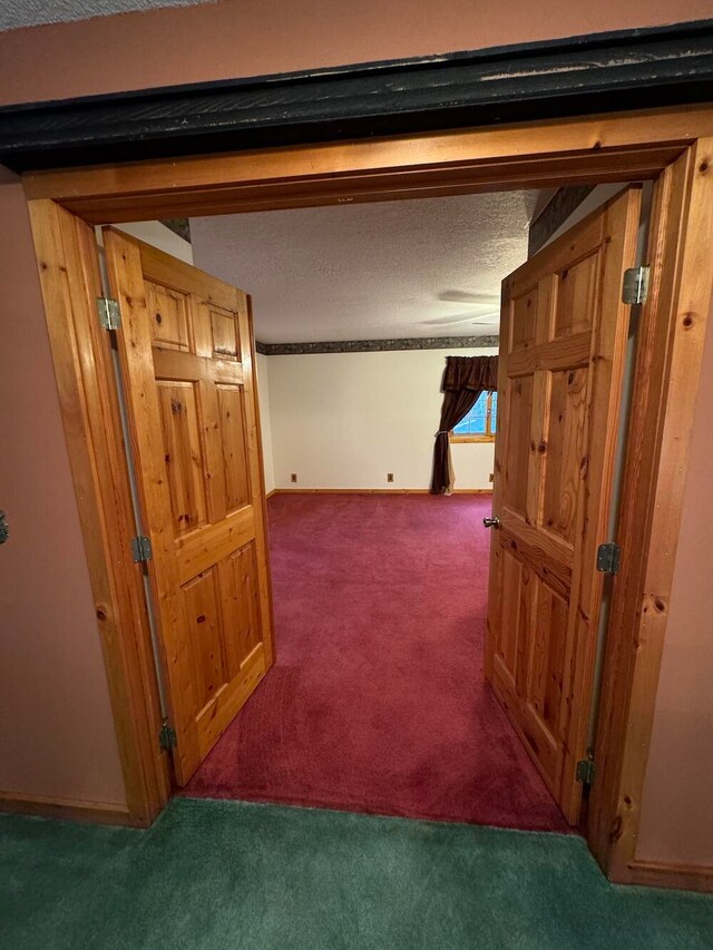 corridor featuring dark colored carpet and a textured ceiling