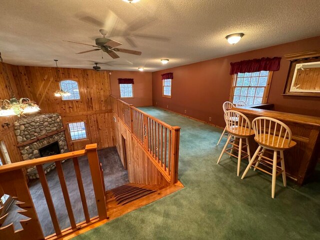 interior space featuring wooden walls, a textured ceiling, ceiling fan, and a fireplace