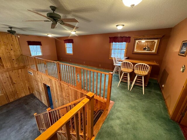 interior space featuring wood walls, carpet, and a textured ceiling