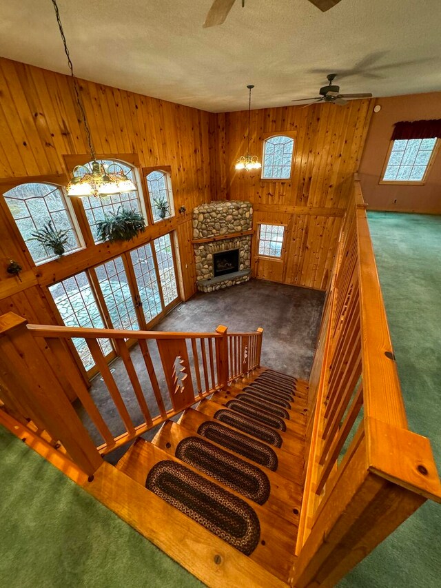 staircase with wood walls, a fireplace, and carpet