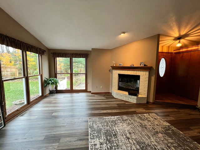 unfurnished living room featuring a brick fireplace, wood-type flooring, a textured ceiling, and vaulted ceiling