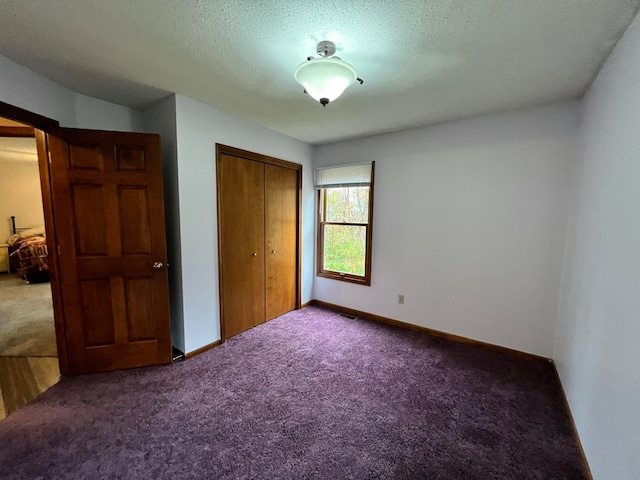 unfurnished bedroom featuring a textured ceiling, carpet floors, and a closet