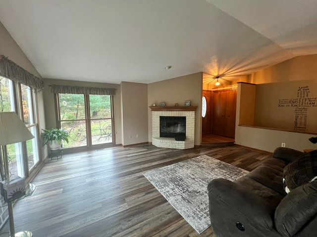 living room with a fireplace, hardwood / wood-style floors, lofted ceiling, and a healthy amount of sunlight