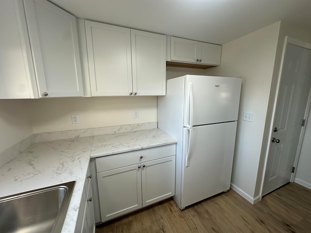 kitchen featuring white cabinets, white refrigerator, sink, dark hardwood / wood-style floors, and light stone countertops