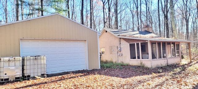 view of property exterior with an outbuilding, a garage, and a sunroom